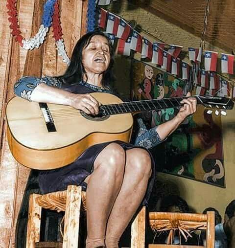 Violeta Parra performing with her guitar under Chilean flags